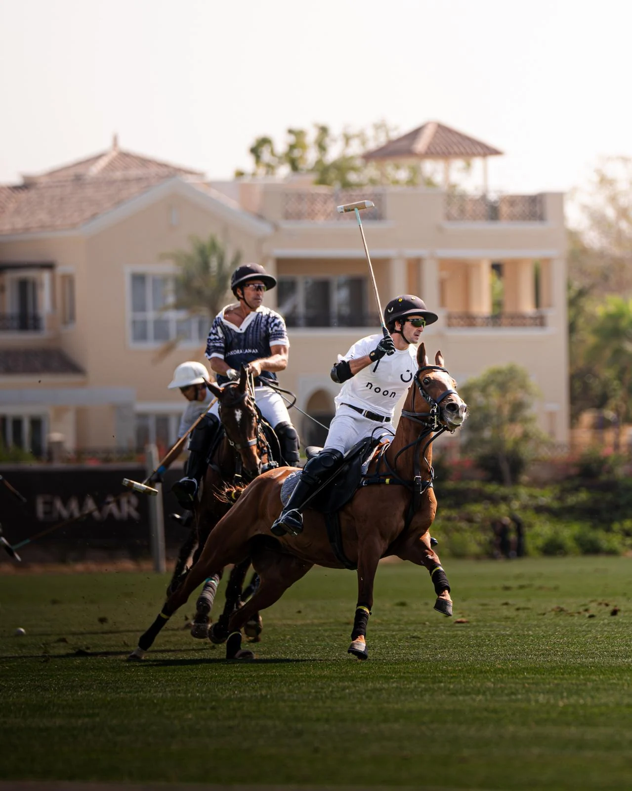 Polo players on horseback in front of a villa